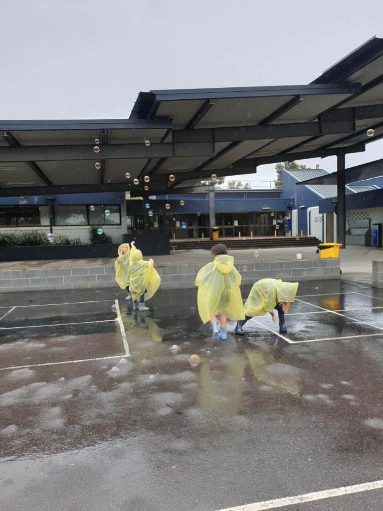 four children wearing raincoats in playground